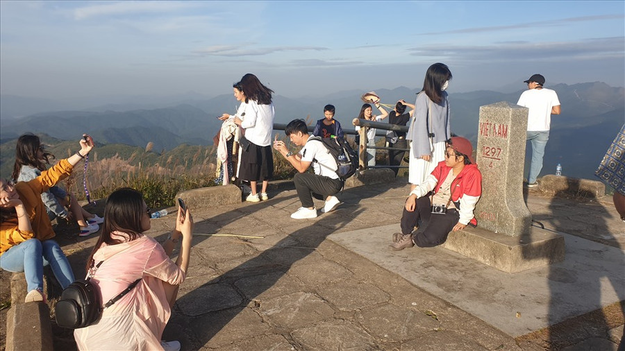  Du khách chụp ảnh trên một cột mốc biên giới, xung quanh một màu trắng của bạt ngàn hoa lau. Ảnh: Nguyễn Hùng