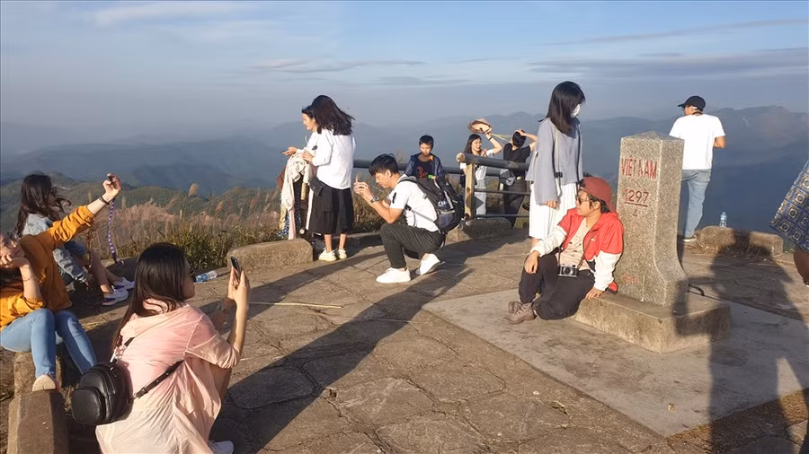  Du khách chụp ảnh trên một cột mốc biên giới, xung quanh một màu trắng của bạt ngàn hoa lau. Ảnh: Nguyễn Hùng