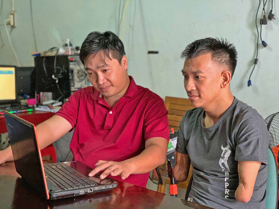 Anh Trần Chí Hải (bìa trái) hướng dẫn em Đào Quốc Việt làm việc. Ảnh: Hồng Thương