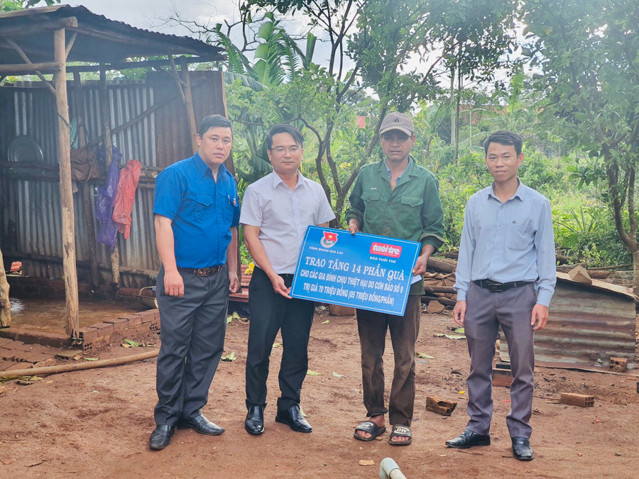 Anh Đỗ Duy Nam (thứ 2 từ trái qua)-Phó Bí thư Tỉnh Đoàn trao tiền hỗ trợ của Báo Tuổi trẻ cho gia đình ông Thunh (thứ 2 từ phải qua) bị thiệt hại do cơn bão số 9. Ảnh: Phan Lài