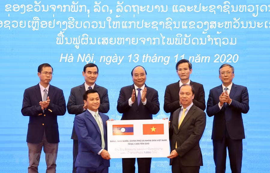 Thứ trưởng Bộ Ngoại giao Nguyễn Quốc Dũng (bên phải) trao tượng trưng 1.000 tấn gạo cho đại diện Đại sứ quán Lào tại Việt Nam trước sự chứng kiến của Thủ tướng Nguyễn Xuân Phúc.