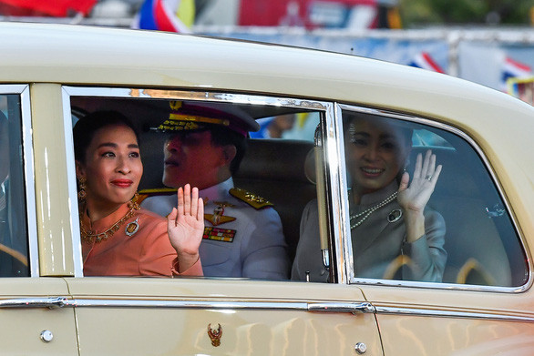  Nhà vua Rama X cùng hoàng hậu Suthida và công chúa Bajrakitiyabha (trái) vẫy tay chào những người thuộc phe bảo hoàng - Ảnh: REUTERS