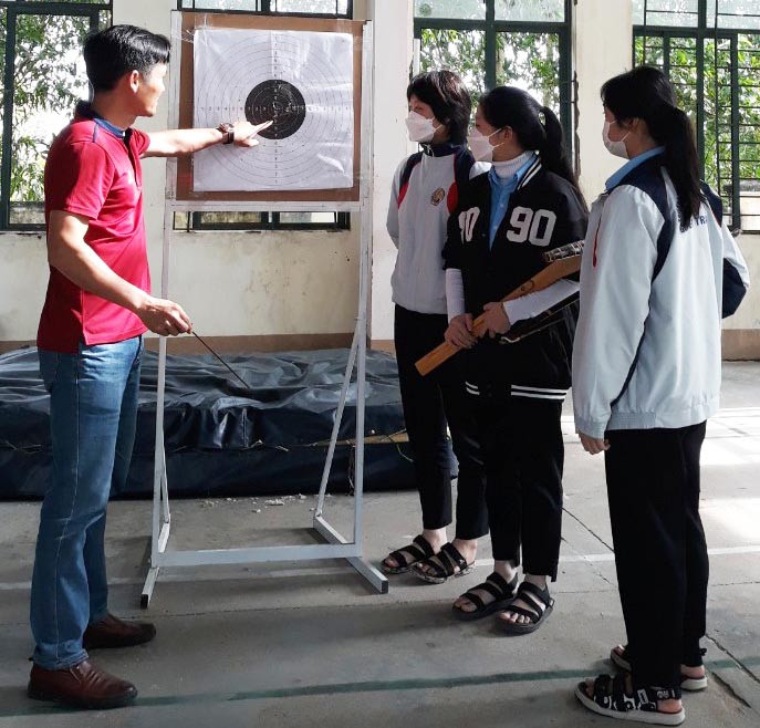 Huấn luyện viên Trường THPT Nguyễn Trãi hướng dẫn kỹ thuật bắn nỏ cho học sinh. Ảnh: Ngọc Minh