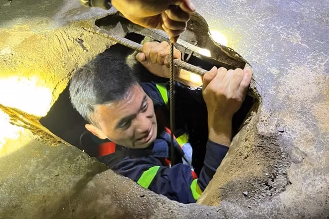 Chiến sĩ cảnh sát chui xuống giếng để cứu 2 bố con. Ảnh: Công an cung cấp