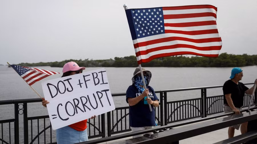 Một số người ủng hộ ông Trump giơ bảng tố cáo Bộ Tư pháp (DOJ) và FBI có hành vi lũng đoạn quyền lực trong vụ xét nhà ông Trump. Ảnh: Reuters