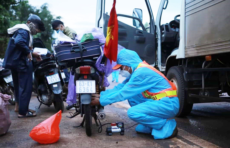 Thành viên CLB Hỗ trợ giao thông SOS Gia Lai sửa xe giúp người dân trên đường về quê tránh dịch Covid-19. Ảnh: SOS Gia Lai cung cấp Ảnh: Như Nguyện