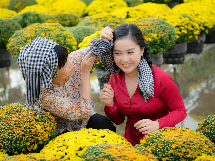 Bạn Thùy Dương, du khách đến từ An Giang, chụp ảnh kỷ niệm bên ruộng cúc mâm xôi. Sắc vàng tươi cùng kiểu dáng tỏa tròn của hoa tượng trưng cho sự sung túc, sum vầy là lý do khiến nhiều người chơi hoa kiểng yêu thích trong dịp năm mới. Ảnh: HUỲNH PHƯƠNG/PHOTOS.MEKONG.DELTA