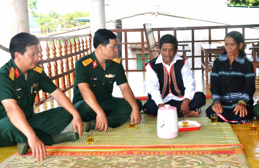 Già làng Siu Tới (bìa phải) trao đổi với cán bộ Công ty 74 về việc xây dựng làng nông thôn mới. Ảnh: Vĩnh Hoàng 