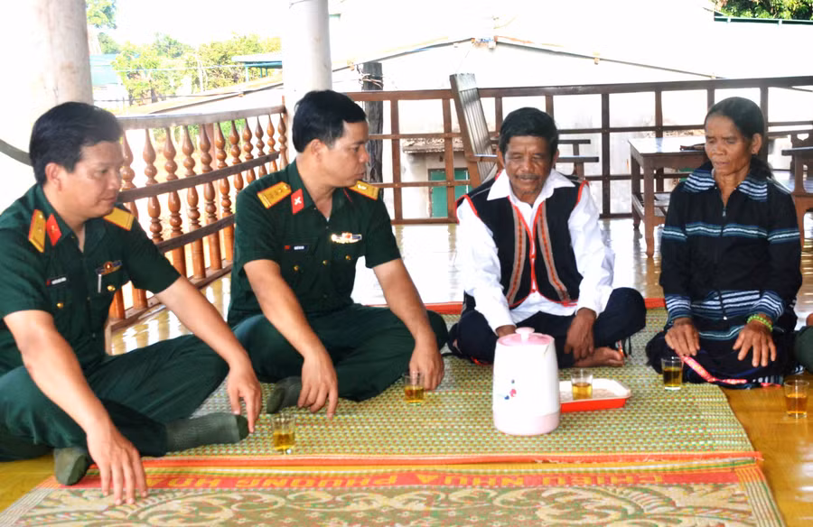 Già làng Siu Tới (bìa phải) trao đổi với cán bộ Công ty 74 về việc xây dựng làng nông thôn mới. Ảnh: Vĩnh Hoàng 