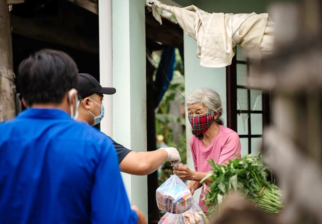 Các bạn trẻ trao thực phẩm cho những người dân có hoàn cảnh khó khăn ẢNH: NAM THỊNH