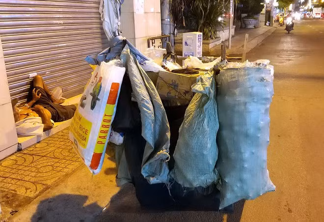 Một người lượm ve chai dựng xe ngoài đường, ngủ mê mệt