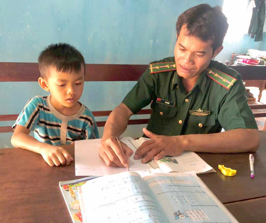 Trung úy Siu Nhin đang hướng dẫn cậu con nuôi, Kpuih Trí học tập. Ảnh: Phương Dung