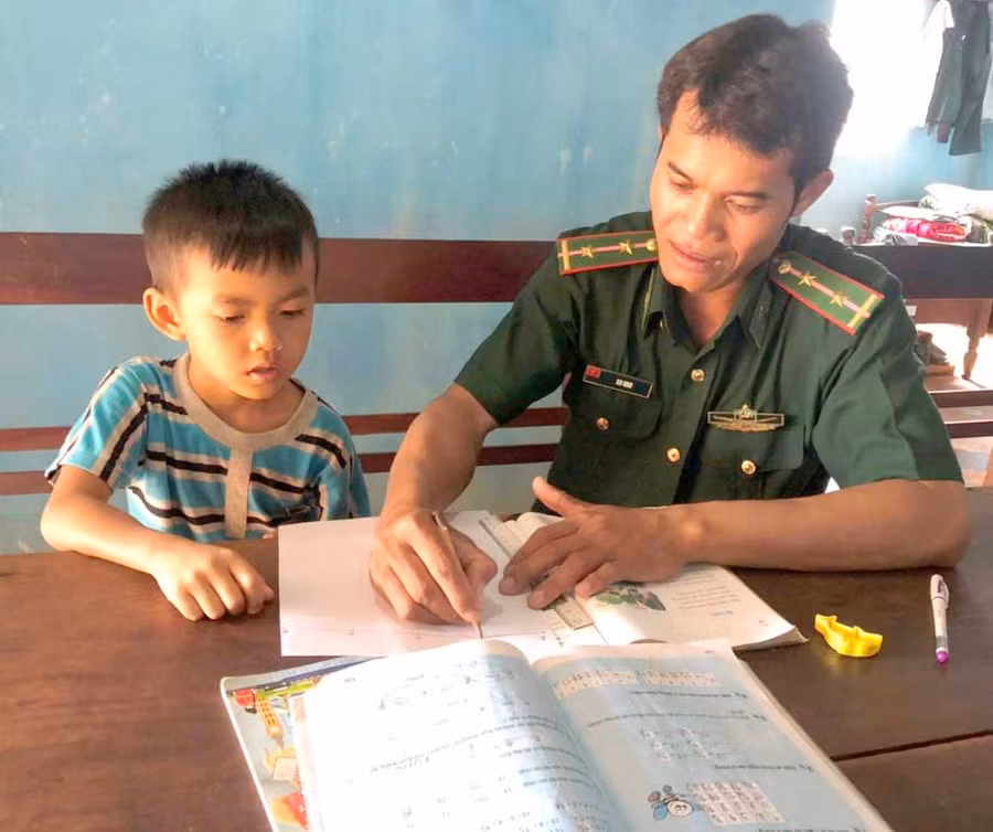 Trung úy Siu Nhin đang hướng dẫn cậu con nuôi, Kpuih Trí học tập. Ảnh: Phương Dung