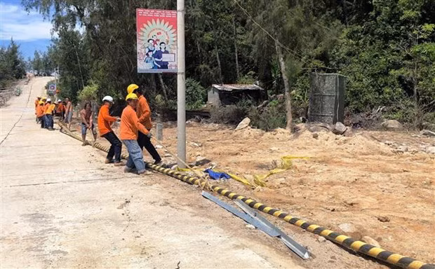 Công nhân Công ty Trách nhiệm hữu hạn Xây dựng điện Thái Dương kéo đường dây cáp ngầm lên đảo Nhơn Châu. (Ảnh: Nguyên Linh/TTXVN)