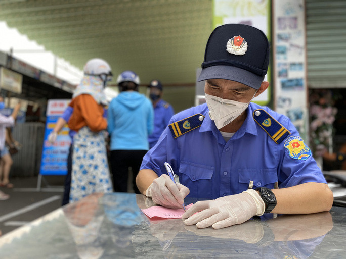 Bảo vệ chợ Cồn điền thông tin vào phiếu giúp người dân trước khi vào chợ