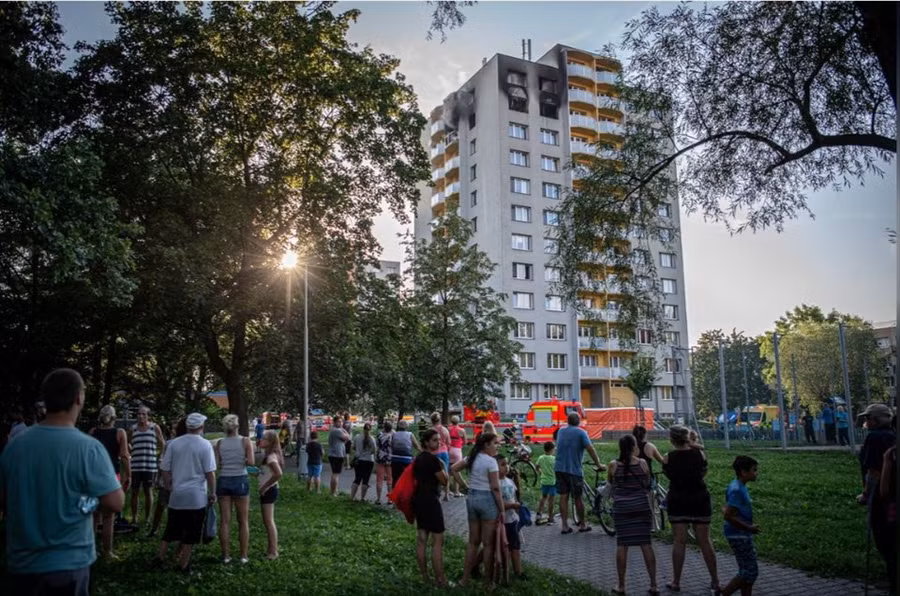  Người dân đứng quan sát dưới chân tòa chung cư bị cháy hôm 8.8 ở thị trấn Bohumin, Cộng hòa Czech. Ảnh: Reuters