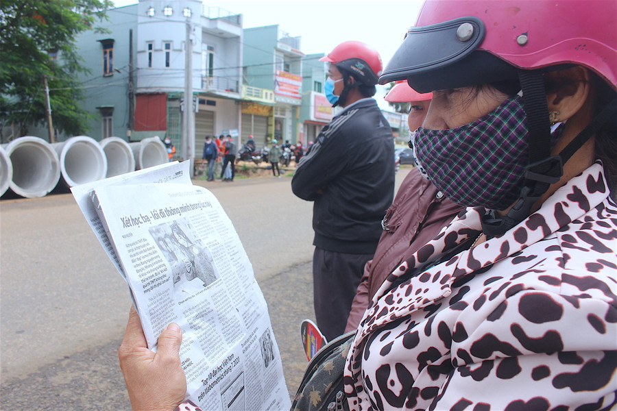 Phụ huynh đọc báo cập nhật thông tin trong thời gian đợi con thi. Ảnh: Nguyễn Giang