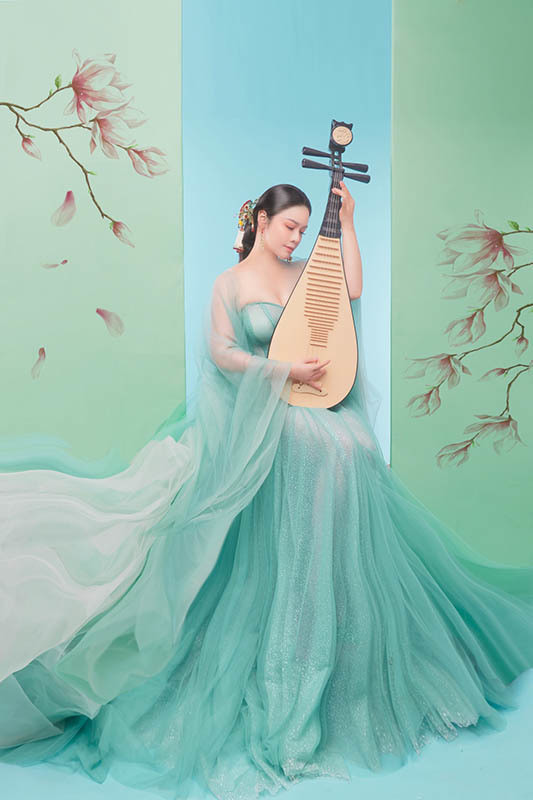 Bà mẹ một con tạo dáng e ấp bên nhành hoa xanh, cây đàn... khoe khéo thân hình quyến rũ cùng thần thái chuẩn mỹ nhân phim cổ trang.