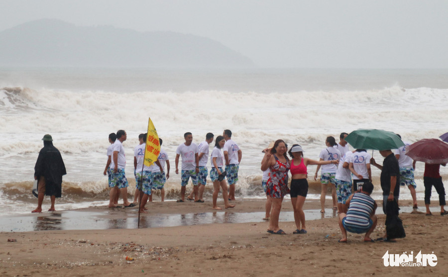 Một nhóm du khách nô đùa bên sóng lớn dù có lực lượng cứu hộ nhắc nhở - Ảnh: DOÃN HÒA