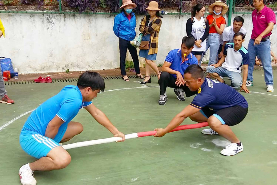 Y Khưm (người đang ngồi chỉ tay) bên VĐV của mình đang thi đấu. Ảnh: Hà Phương