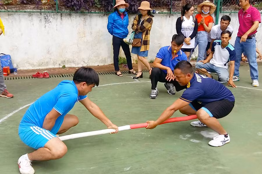 Y Khưm (người đang ngồi chỉ tay) bên VĐV của mình đang thi đấu. Ảnh: Hà Phương