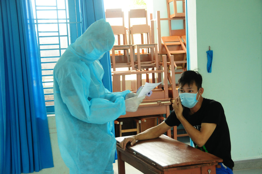 Cán bộ y tế tại khu cách ly Trường Lương Thế Vinh kiểm tra sức khỏe cho một người mới vào - Ảnh: B.D