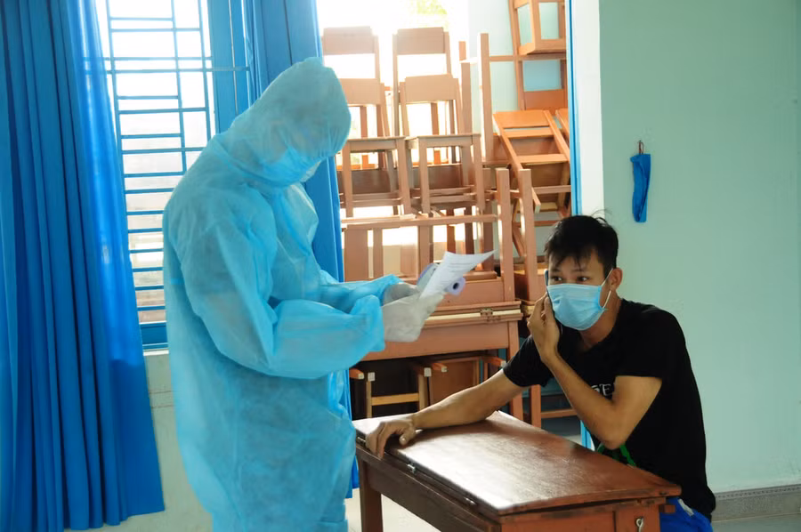 Cán bộ y tế tại khu cách ly Trường Lương Thế Vinh kiểm tra sức khỏe cho một người mới vào - Ảnh: B.D