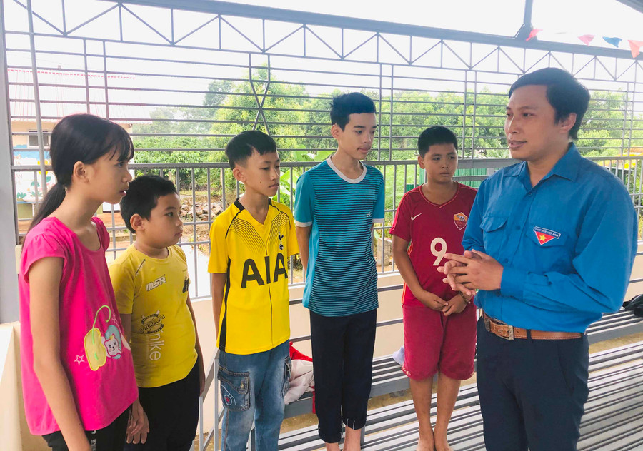 Anh Lều Vũ Thanh (bìa phải) vận động các em thiếu nhi tham gia lớp dạy bơi miễn phí. Ảnh: Thủy Bình 