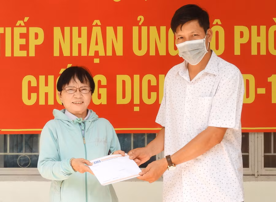  Bà Mai Thị Nữu (trái) trao tiền tiết kiệm của cá nhân ủng hộ các thầy thuốc đang làm công tác chống dịch Covid-19 tại Đà Nẵng. Ảnh: Thanh Nhật