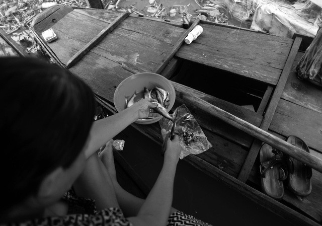 Bà Hinh làm sạch mấy con cá chồng vừa đi đánh về để nấu bữa trưa. Những hôm đánh được cá, gia đình bà có thêm thức ăn còn không thì họ đi dọc sông hái ít rau dại về luộc lên ăn cho qua.