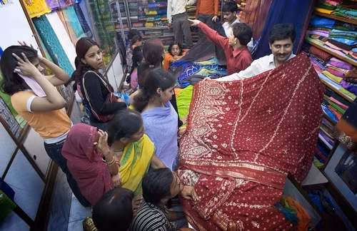 Những người phụ nữ mua vải để may những bộ Sari truyền thống từ những người đàn ông.