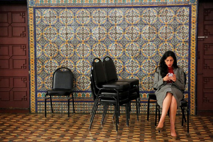 Nữ trợ lý chăm chú nhìn vào màn hình di động trong lúc bà Clinton tổ chức họp báo sau cuộc vận động tranh cử ở Zembo Shrine.