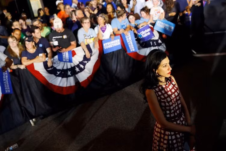 Trợ lý cấp cao Huma Abedin đứng ở phía dưới sân khấu nhìn lên khi bà Clinton cùng phó tướng Tim Kaine vận động ở Harrisburg, Pennsylvania.