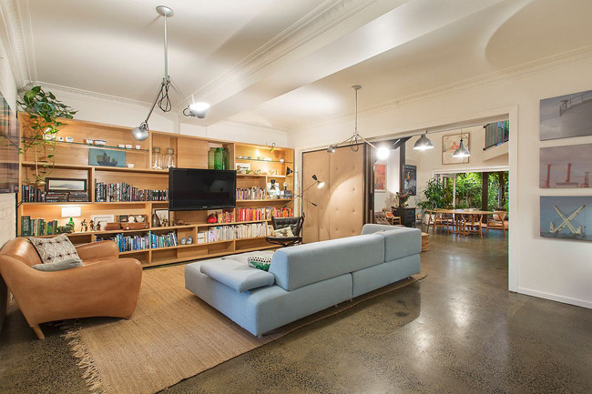 Phòng khách nằm đối diện với khoảng sân bên ngoài. Kệ tivi kiêm tủ sách lớn là thiết kế thông minh, vừa tiết kiệm diện tích, vừa mang lại màu sắc mới mẻ cho căn phòng.