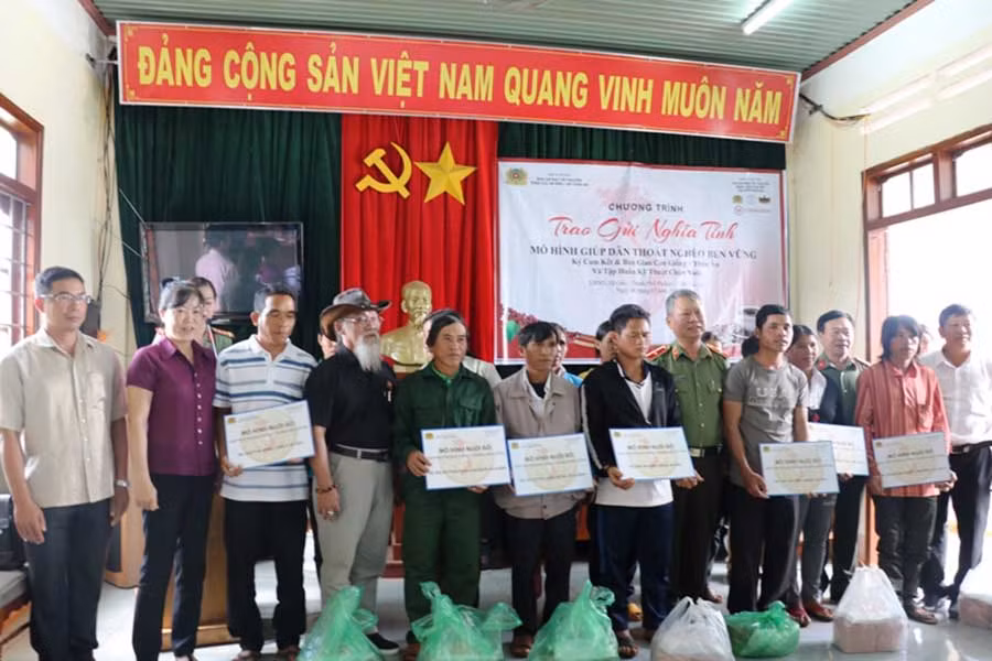 Lãnh đạo Cục An ninh và Công ty TNI Corporation trao bảng tượng trưng nhận bò cho các hộ dân.