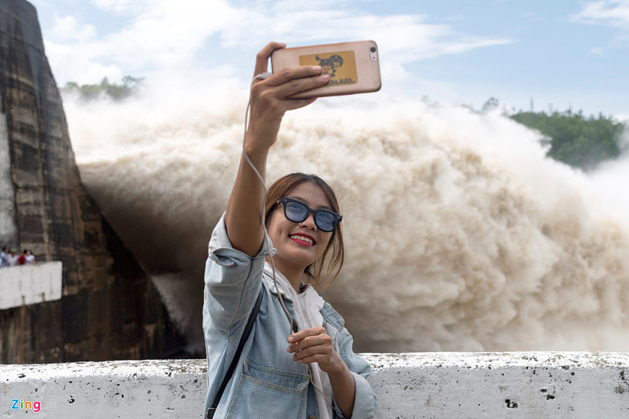 Một cô gái thích thú chụp ảnh với cảnh "sóng thần" cuồn cuộn. Một cô gái thích thú chụp ảnh với cảnh