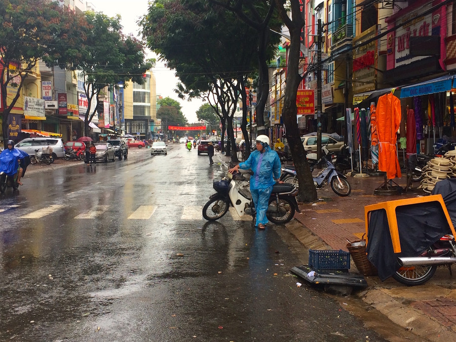 Ông Thành kiên nhẫn đợi khách trong mưa bên góc đường Hoàng Văn Thụ. Ảnh: Hồng Thi