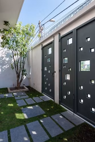 Cổng chính cũng là không gian xanh và ăn nhập với ngôi nhà khi có nhiều ô vuông nhỏ rất thông thoáng.