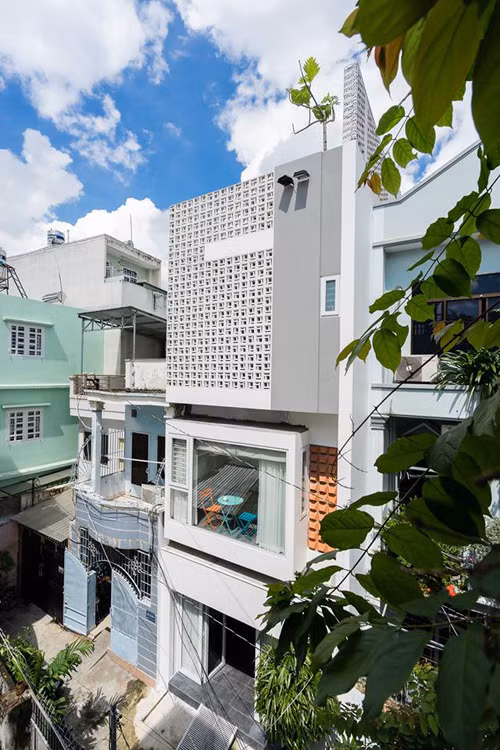 Sau khi hoàn thiện, ngôi nhà ống 4 tầng ở quận Phú Nhuận (TP HCM) nổi bật giữa con hẻm gồm những công trình xây kiểu cũ. Mặt tiền phối hợp hài hòa giữa gạch lỗ, ô cửa kính khiến nhà trông giống như một khối hộp đồ chơi xinh xắn.