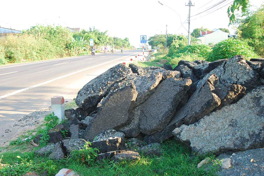 Những mảng bê tông nhựa chất thành đống trên hành lang quốc lộ 14 dễ gây nguy hiểm cho người điều khiển phương tiện giao thông. Những mảng bê tông nhựa chất thành đống trên hành lang quốc lộ 14 dễ gây nguy hiểm cho người điều khiển phương tiện tham gia giao thông.