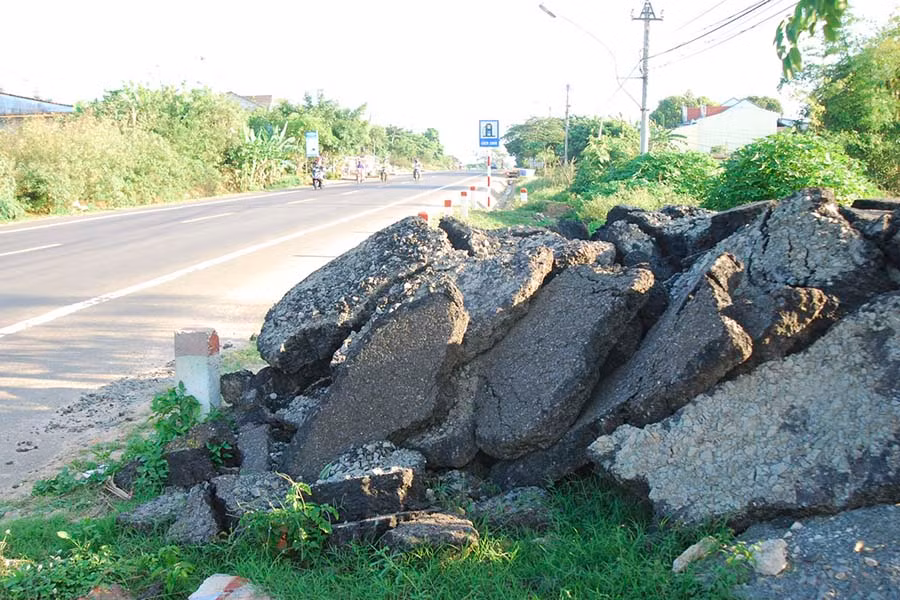Những mảng bê tông nhựa chất thành đống trên hành lang quốc lộ 14 dễ gây nguy hiểm cho người điều khiển phương tiện tham gia giao thông.