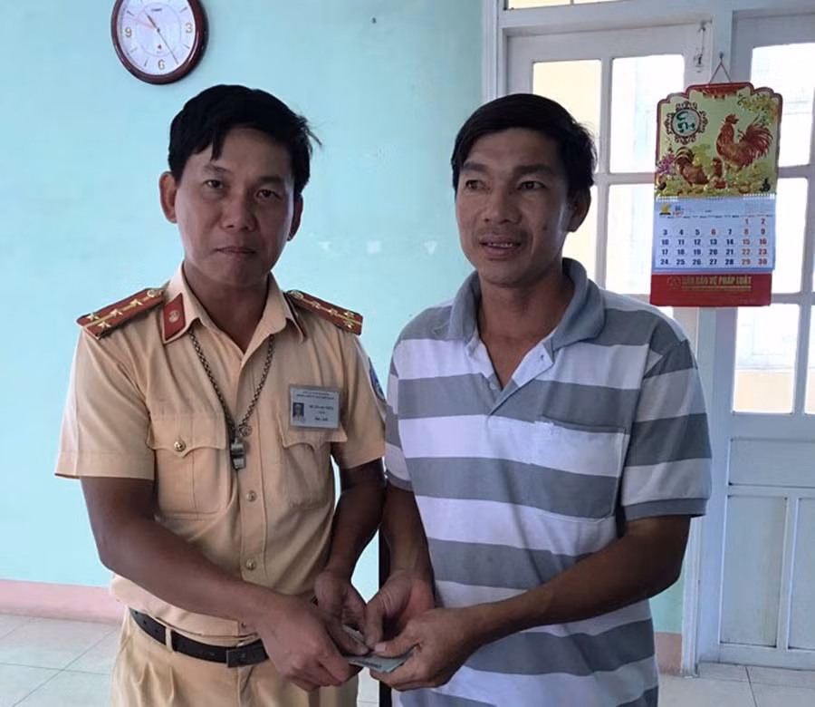  Đại úy Đỗ Thanh Triêm trao lại số tiền anh Mạnh bị đánh rơi (Ảnh CSGT Tuy Phước cung cấp).