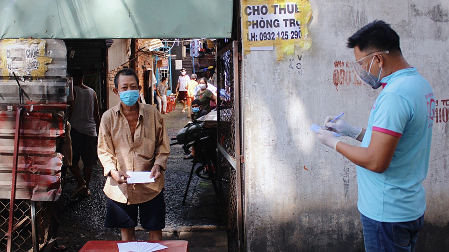 Theo danh sách đã lập trước đó, người dân lần lượt đến nhận quà hỗ trợ của nhóm Thiện nguyện Sài Gòn. Ảnh: ĐÀO NGUYÊN