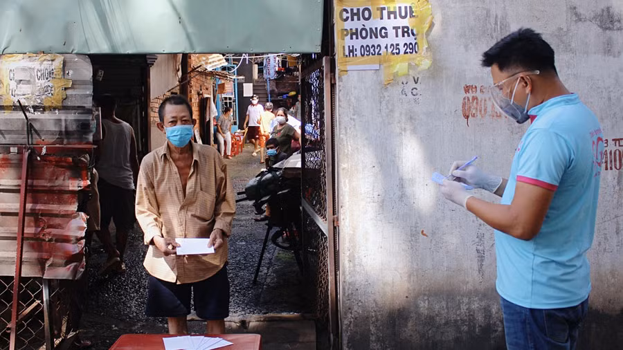 Theo danh sách đã lập trước đó, người dân lần lượt đến nhận quà hỗ trợ của nhóm Thiện nguyện Sài Gòn. Ảnh: ĐÀO NGUYÊN