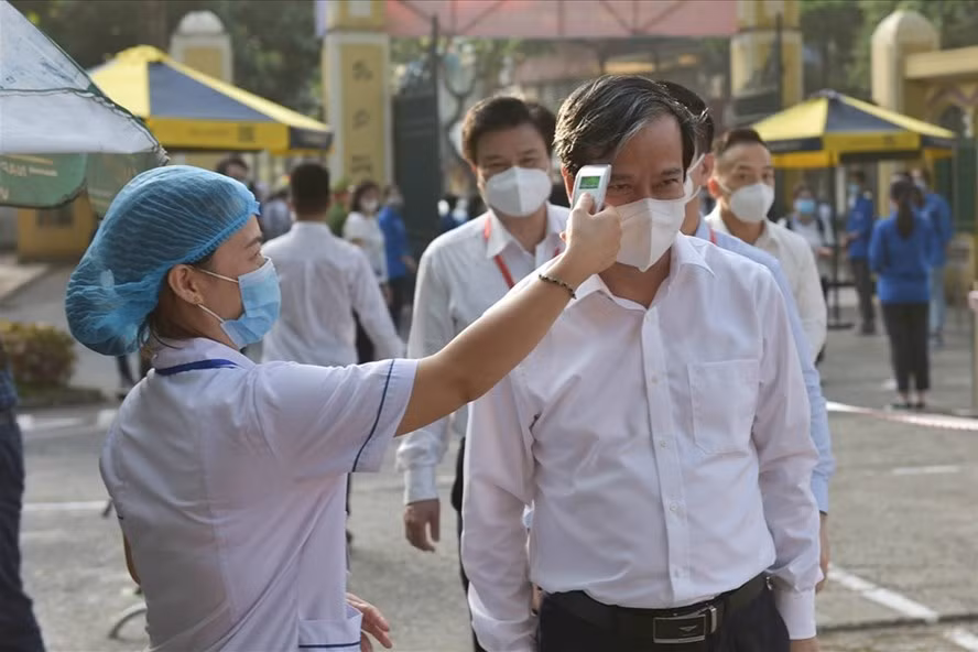 Hình ảnh Bộ trưởng Nguyễn Kim Sơn đo thân nhiệt trước khi vào thị sát Điểm thi Trường THPT Chu Văn An (Hà Nội) ngày 7.7.2021. 