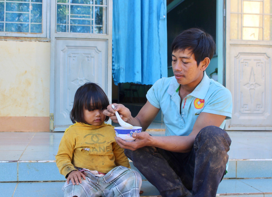 Thấy trường phát cháo cho học sinh, anh Yem đem con gái 2 tuổi đến trường ăn cháo cùng anh chị. Ảnh: Phan Lài