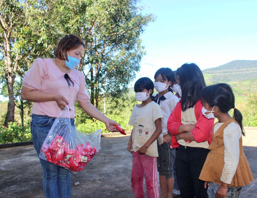 Ngoài phát cháo, cô Hà Thị Thanh Việt (bìa trái) còn tặng bánh kẹo cho các em học sinh. Ảnh: Phan Lài