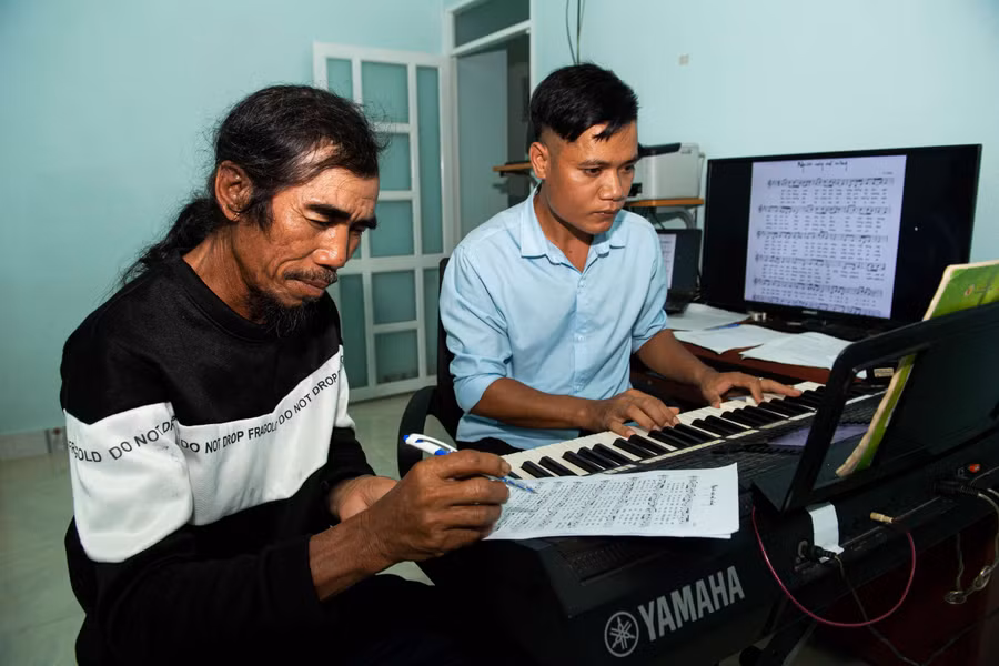 Anh A Thuê đang soạn nhạc cùng ông của mình là nghệ nhân ưu tú A Thui. Ảnh: Đ.T