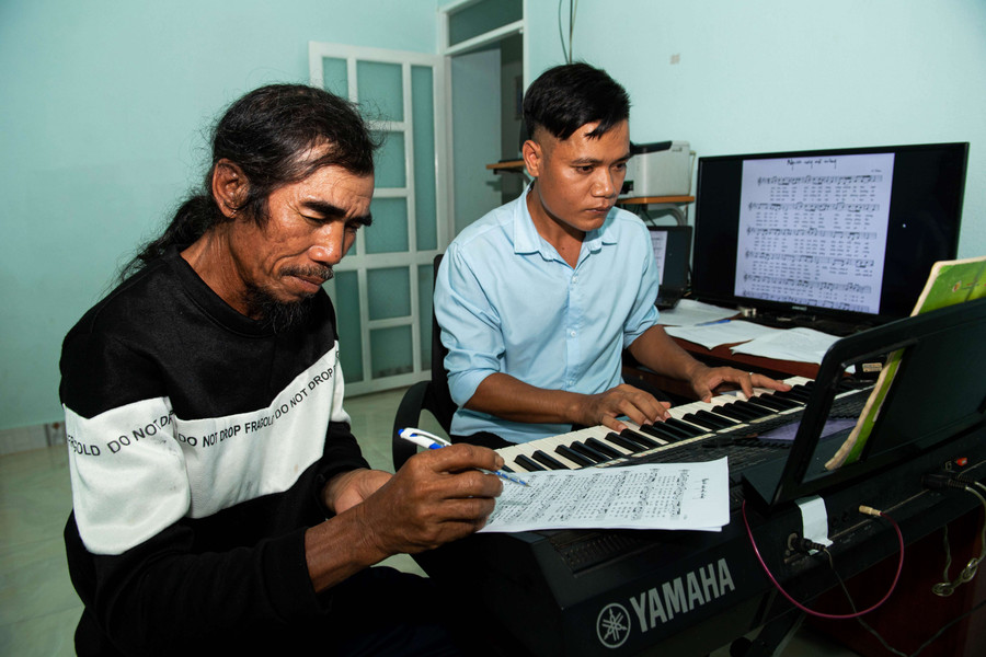 Anh A Thuê đang soạn nhạc cùng ông của mình là nghệ nhân ưu tú A Thui. Ảnh: Đ.T