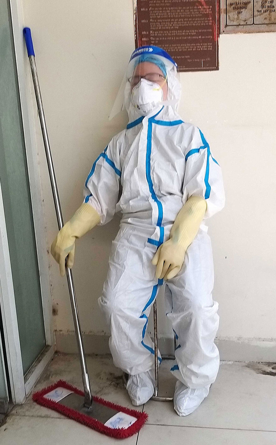 Tình nguyện viên kiệt sức trong bộ đồ bảo hộ khi làm lao công